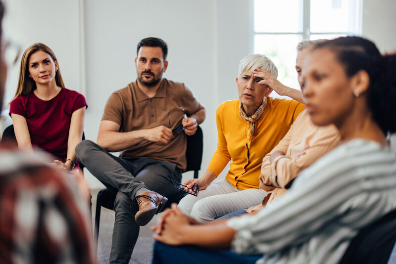 A small group of adults sitting in a circle in a bright room