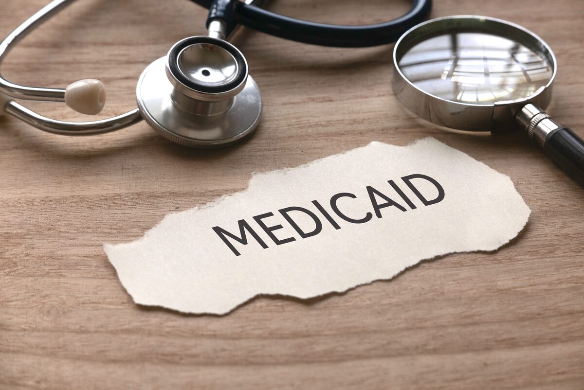 A stethoscope and magnifying glass resting on insurance paperwork — verifying coverage.